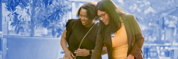Two women looking at check-in table and smiling.