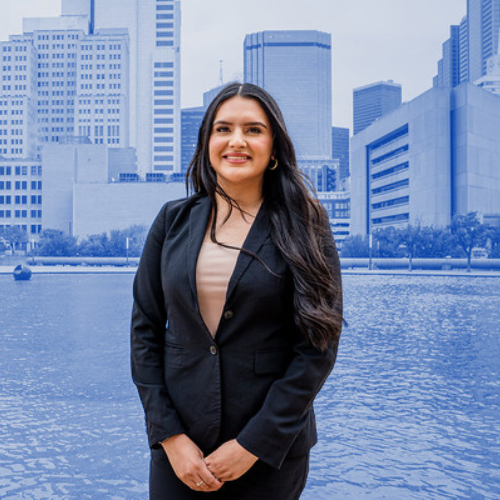 Woman posing and smiling. City view is in the background.