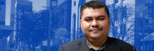 Alum looking at camera and smiling with the city as his background.