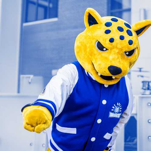 Jax (Jaguar) mascot dancing in front of a building.
