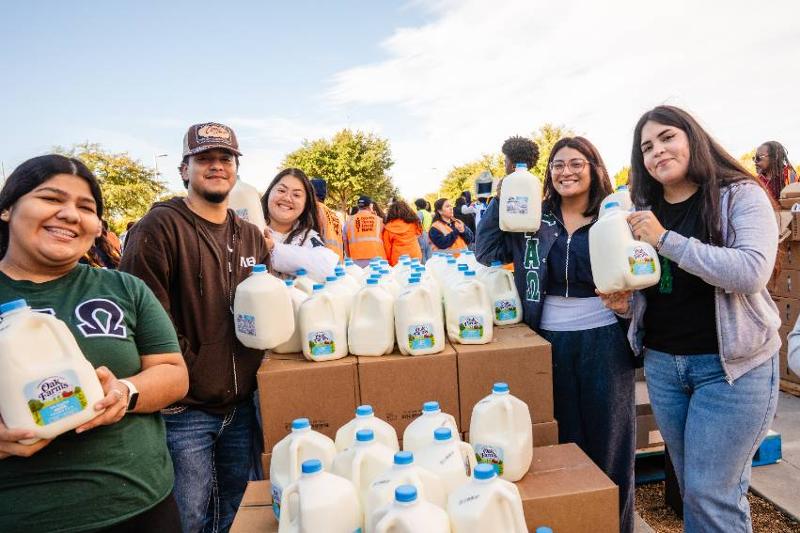 Volunteers Holds Containers of Milk at Monthly Mobile Food Drive Just Before Thanksgiving