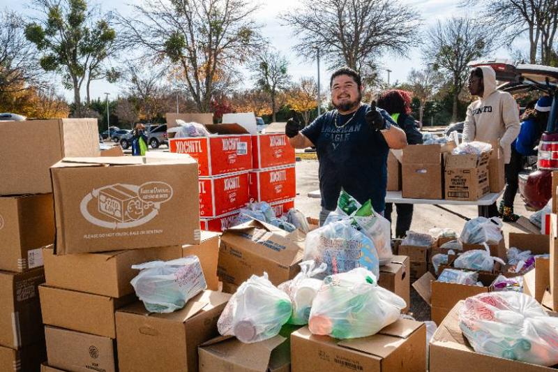 A Volunteer Gives the Thumbs-Up Sign as He Loads Bags of Food To Be Given Away