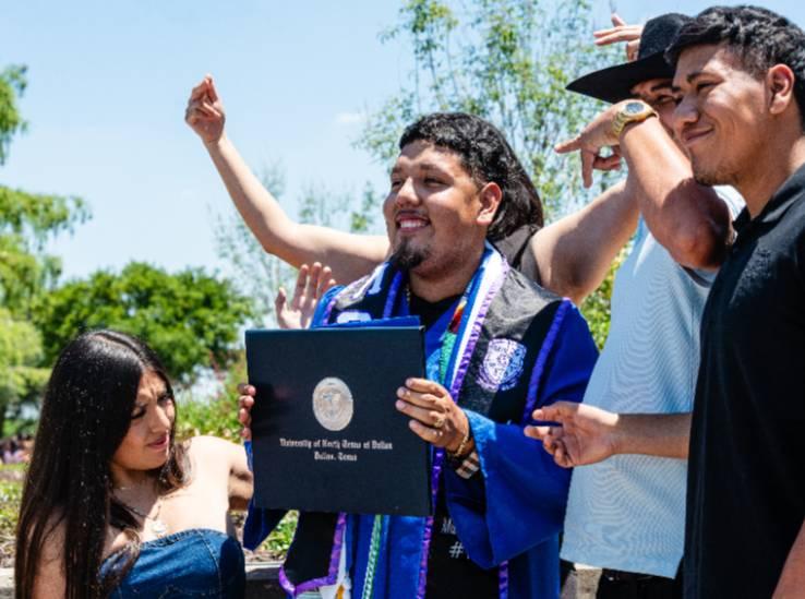 A Student Proudly Holds His Diploma, Surrounded by Family and Friends, at the May 2026 Commencement Ceremony