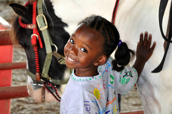 A Young and Caring Hana Pets Horses and Smiles Brightly for the Camera
