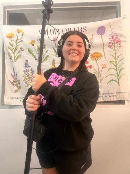 Maddie Mansell Wearing Headphones and Holding Equipment for a Digital Media Project