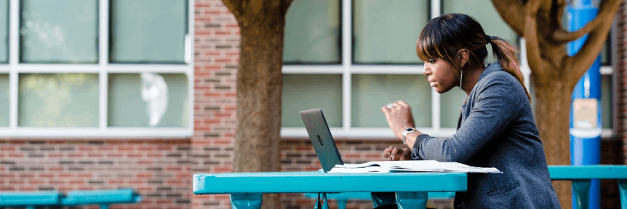 unt dallas graduate student seated in courtyard at laptop