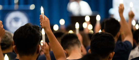 students hold up candles at convocation