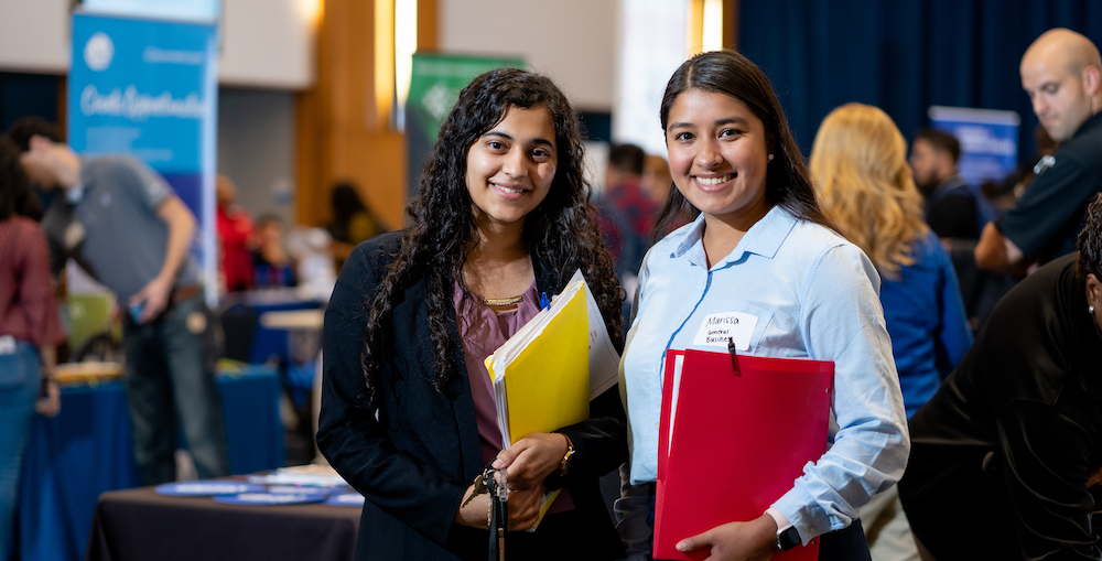 two female students pose for camera at career fair