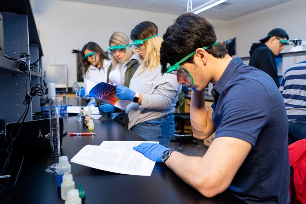 students working in a lab wearing ppe and using science materials