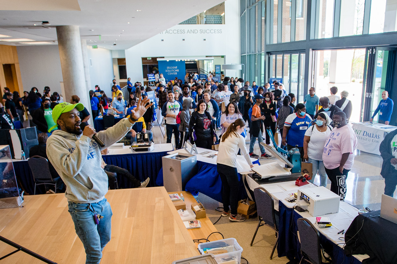 TJ on a stage surrounded by a crowd of students.