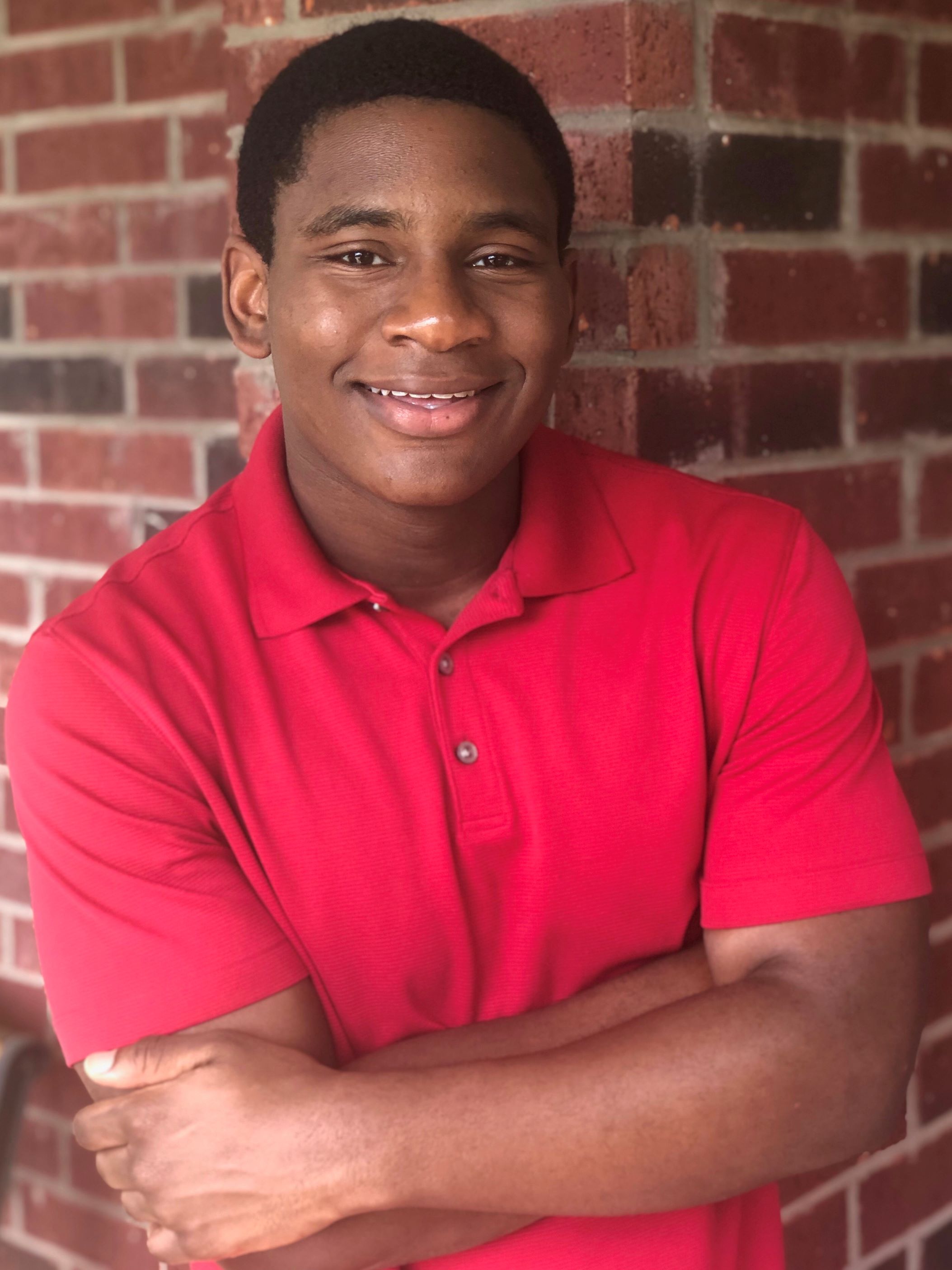 brown male smiling in red collared polo